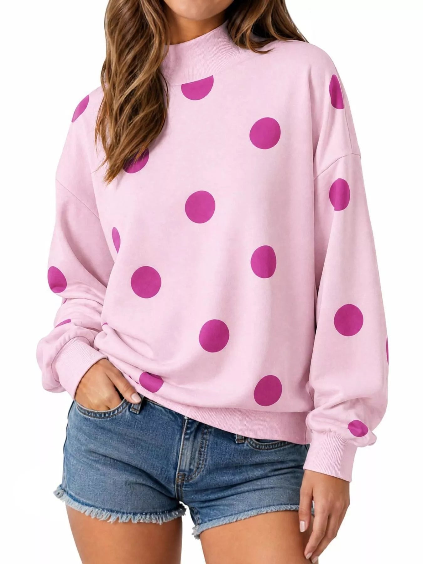 Front view of pink mock neck oversized sweatshirt with large magenta polka dots on model