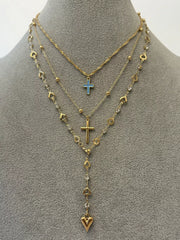 Layered gold necklaces displayed on grey mannequin with blue cross and heart drop