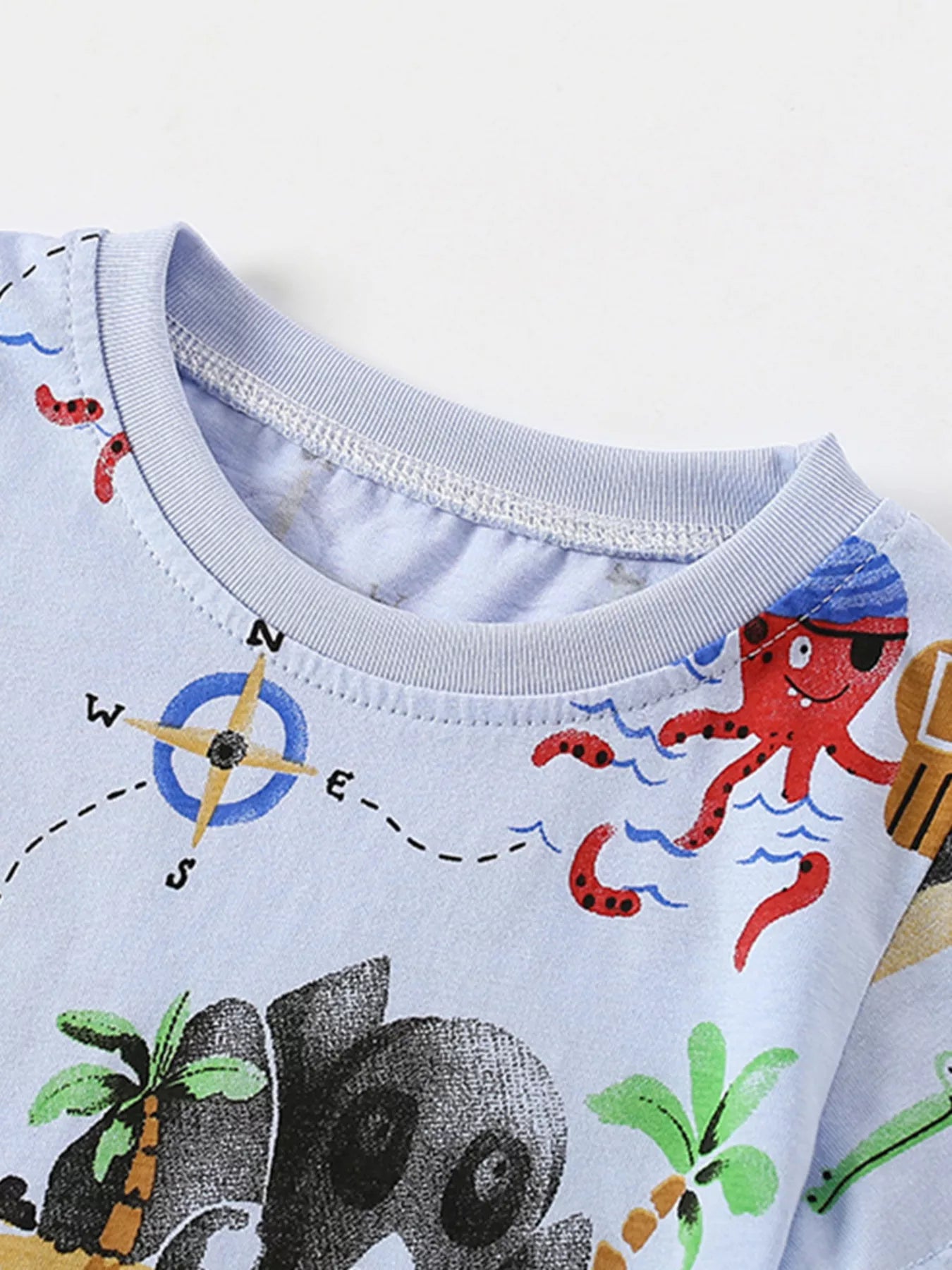 Close-up of the light blue shirt neckline with a compass print and red octopus nearby