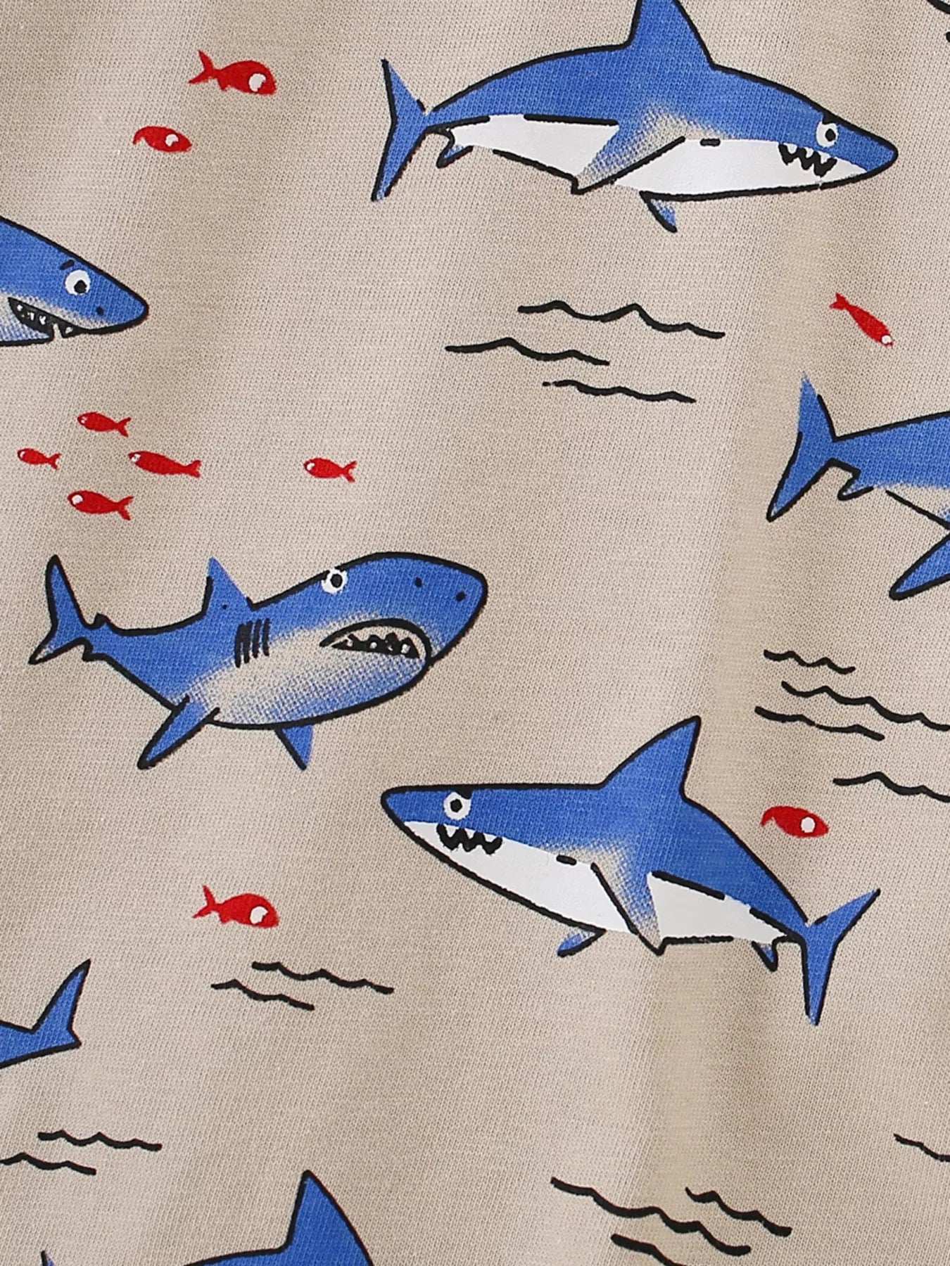 Close-up of blue cartoon sharks and small red fish print on tan children's tee