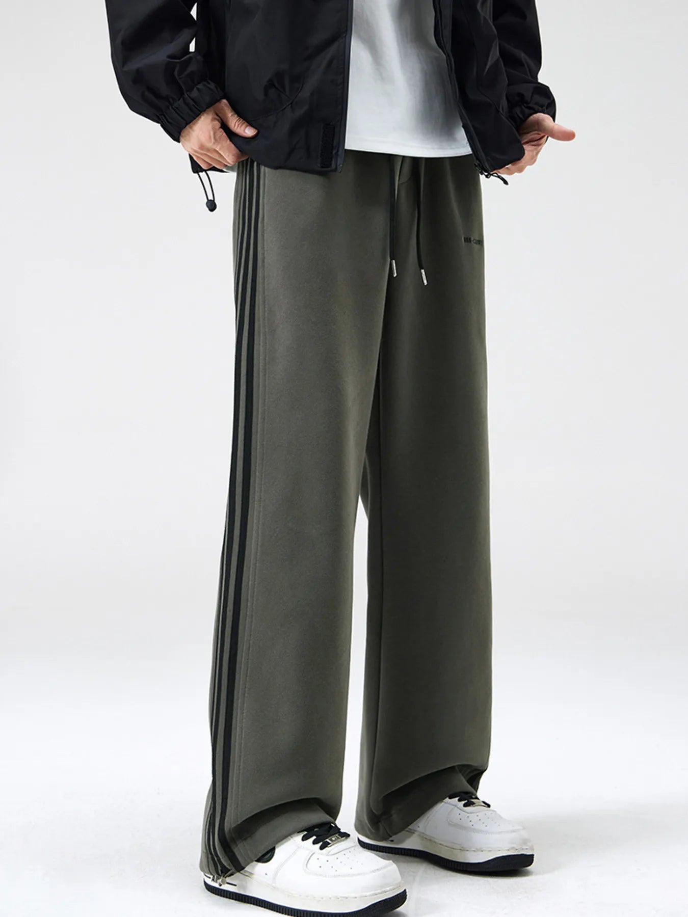 Men's army green relaxed-fit pants with side stripes, a drawstring waist and pockets.