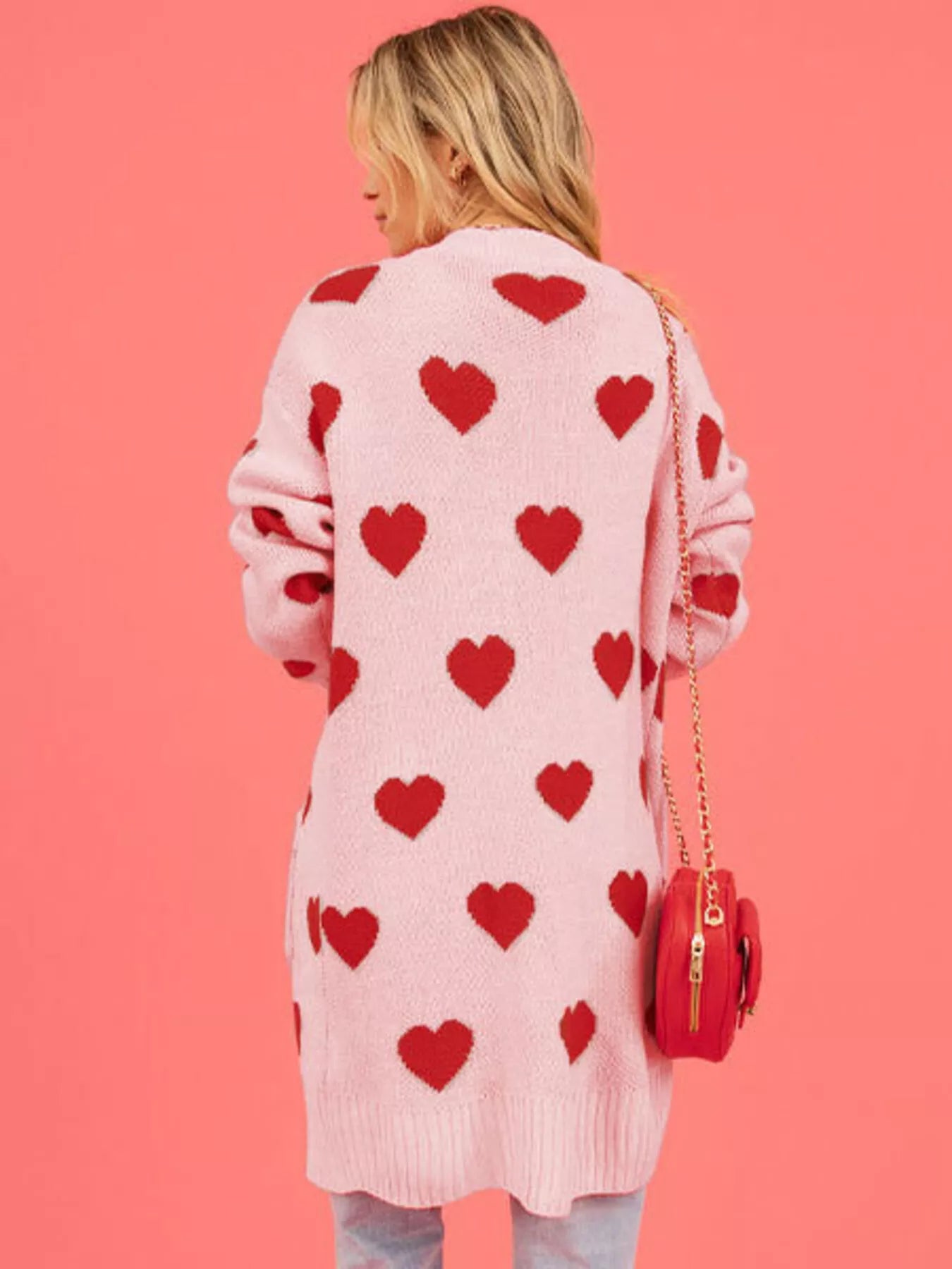 Back view of the pink longline cardigan covered in a red heart pattern