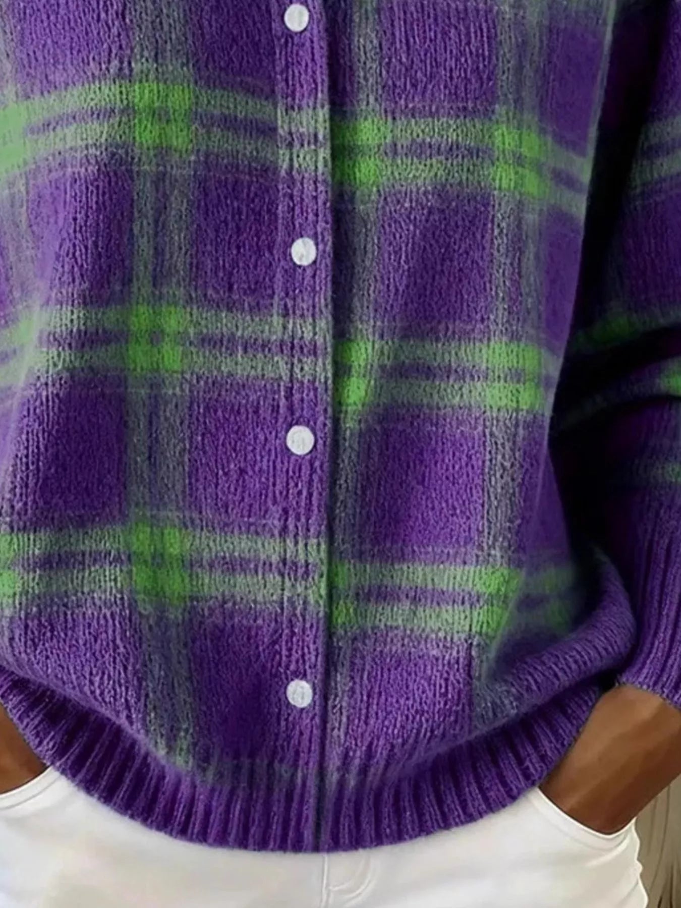 Close-up of the lower front and ribbed hem of a purple and green plaid knit cardigan