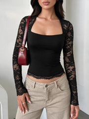 Black square-neck top with sheer floral lace sleeves and scalloped hem, styled with beige pants.