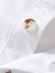 Close detail of a mottled button on the placket of a white children's polo shirt