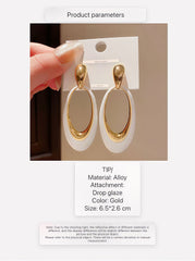 Pendientes colgantes contemporáneos en tono dorado con incrustación ovalada blanca lisa y alargada