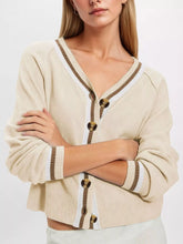 Close-up on-model front view of apricot V neck cardigan with brown and white striped trim