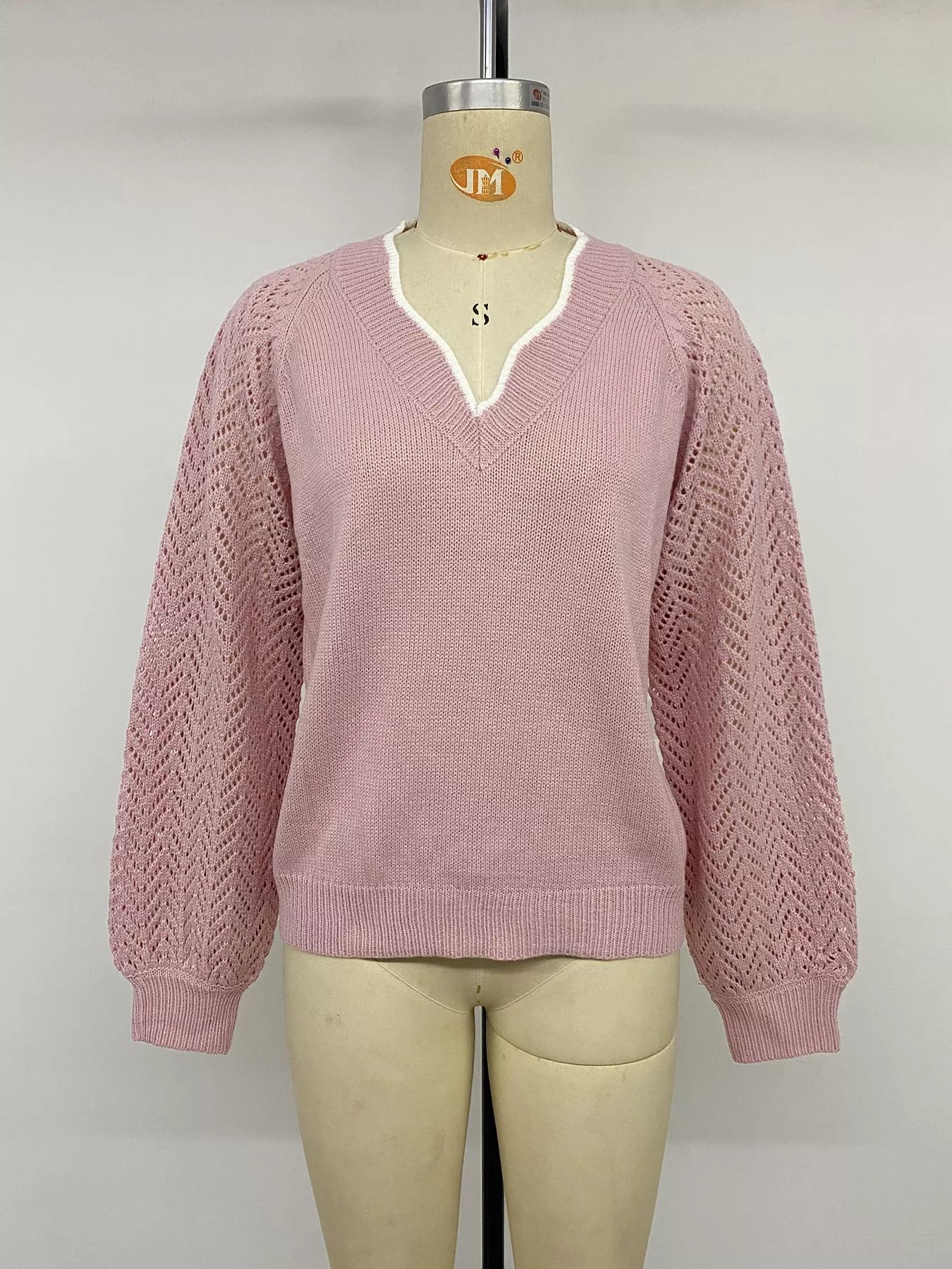 Front view on a mannequin of a pink V neck sweater with openwork long sleeves.