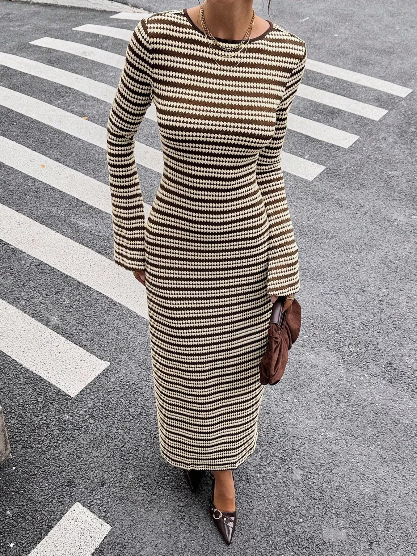 On-model front view of a brown and cream striped sweater dress with flared sleeves