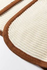 Close up detail of a beige sweater vest curved hem with brown contrast trim