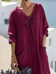 Cropped front view of plum purple long sleeve loose maxi dress, showing tie neck and large pockets