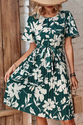 Women's floral pleated dress with a round neckline and tie belt in the Forest color.