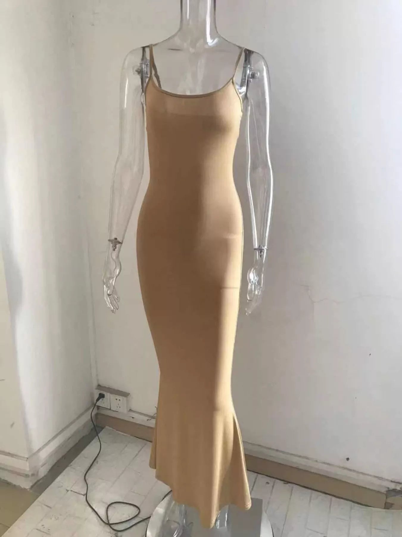 Front view of a camel spaghetti strap bodycon maxi dress displayed on a clear mannequin indoors