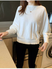 Front view of a white batwing sleeve knit top with vertical seams, worn indoors.