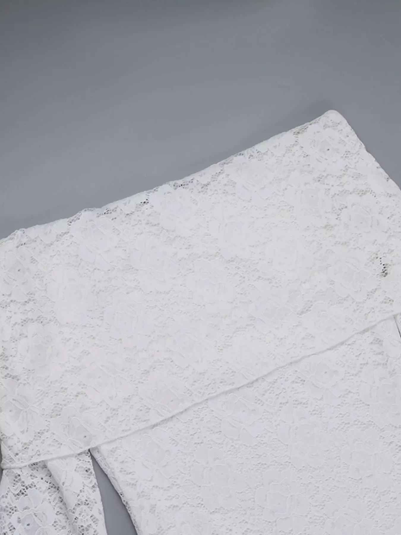 Flat detail view of a white lace maxi dress showing the bodice and skirt seam