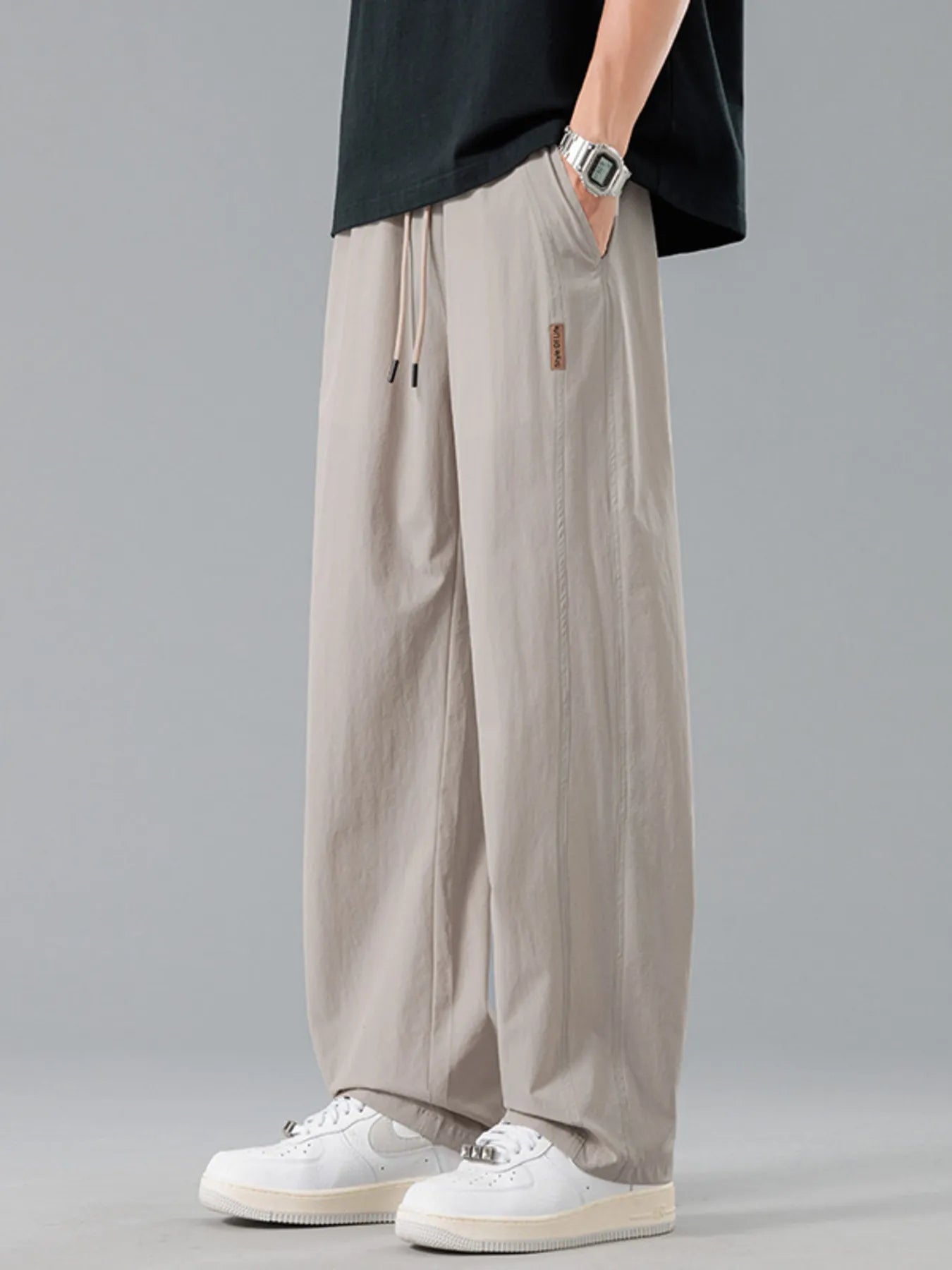 Men's khaki loose-fit casual pants with a drawstring waist and pockets.