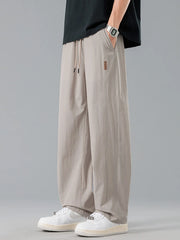 Men's khaki loose-fit casual pants with a drawstring waist and pockets.