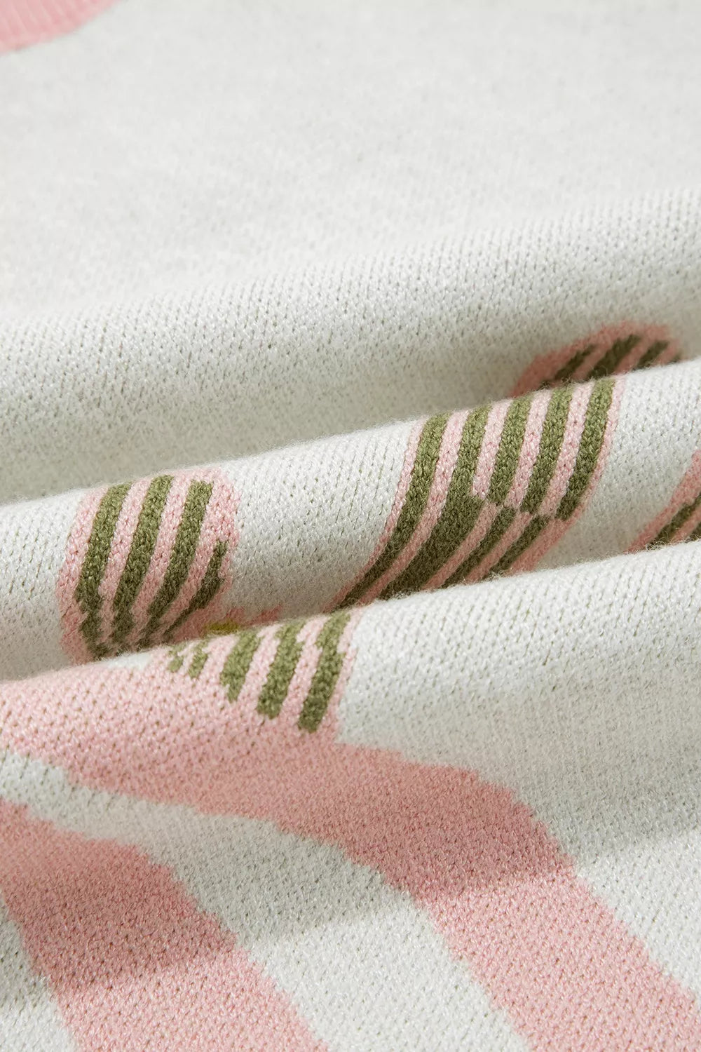 Close-up of folded cream knit fabric with green cactus and pink wave detail