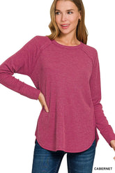 Women's burgundy waffle-knit long-sleeve top with raglan sleeves and rounded hem, modeled with jeans