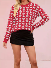 On-model front view of a red knit sweater with white heart and diamond argyle pattern