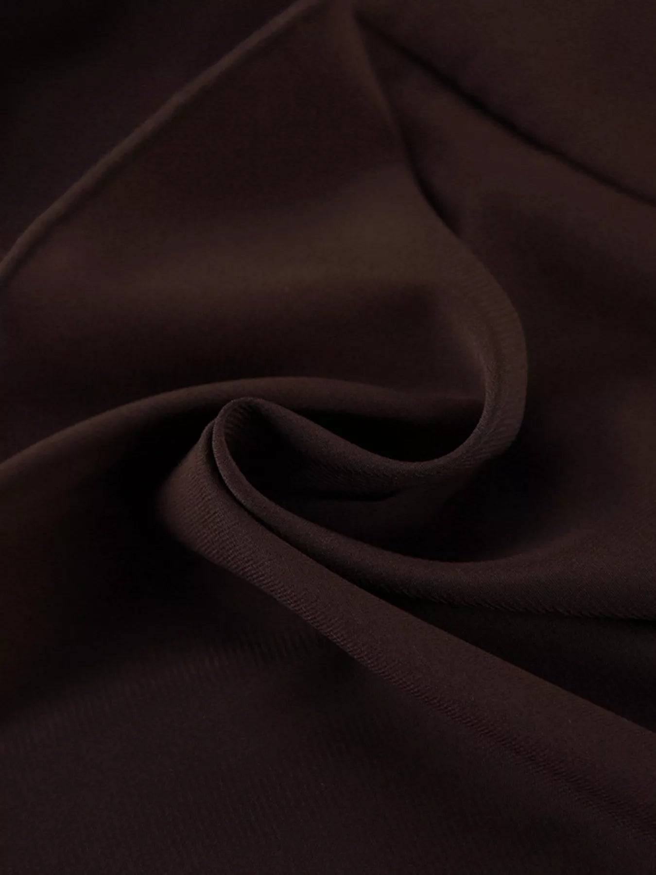 Close detail of brown mini dress fabric folded to show smooth texture
