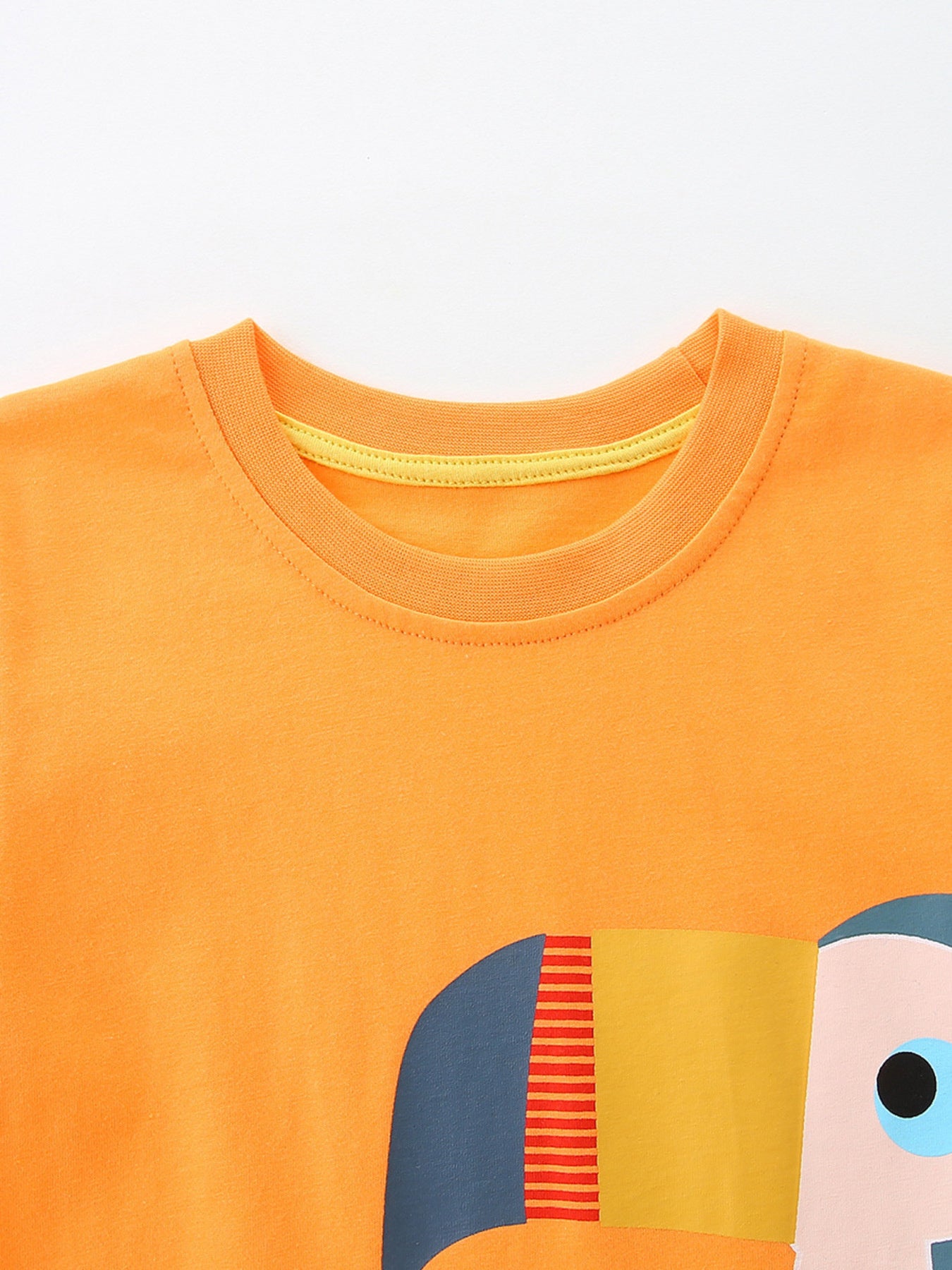 Close-up of orange round neckline with yellow trim and the top of the toucan graphic