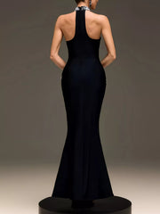 Back view of black sleeveless maxi dress with halter strap on a platform