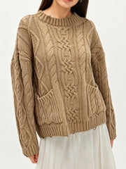 Front view of khaki cable knit sweater with front pockets and white skirt