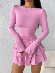 Pink layered ruffle long sleeve mini dress worn front facing with hands together in front