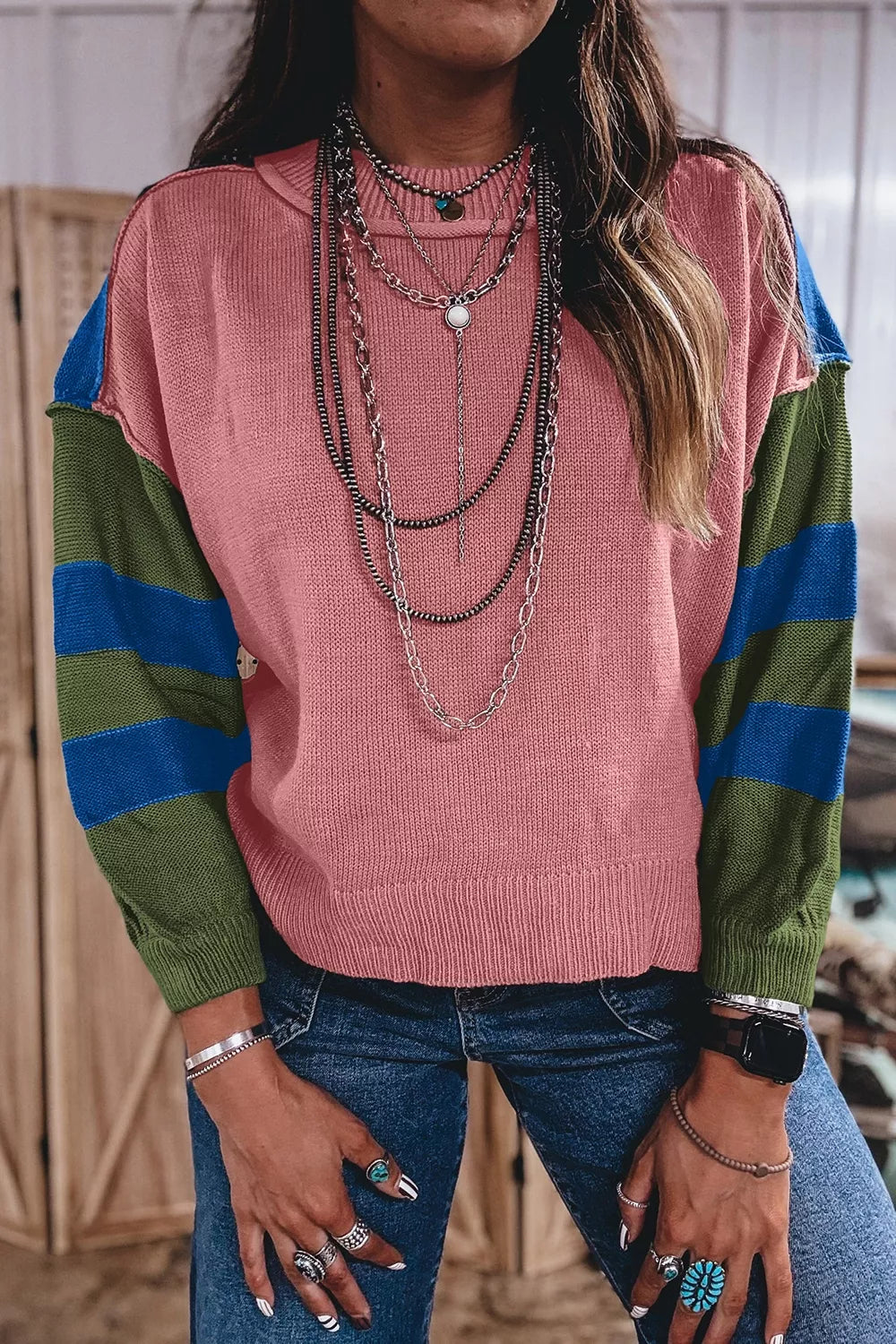 Front view of the dusty pink sweater with bold green and blue striped sleeves