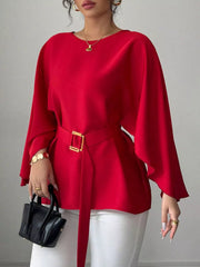 Red round neck blouse close front view holding black handbag with gold buckle belt