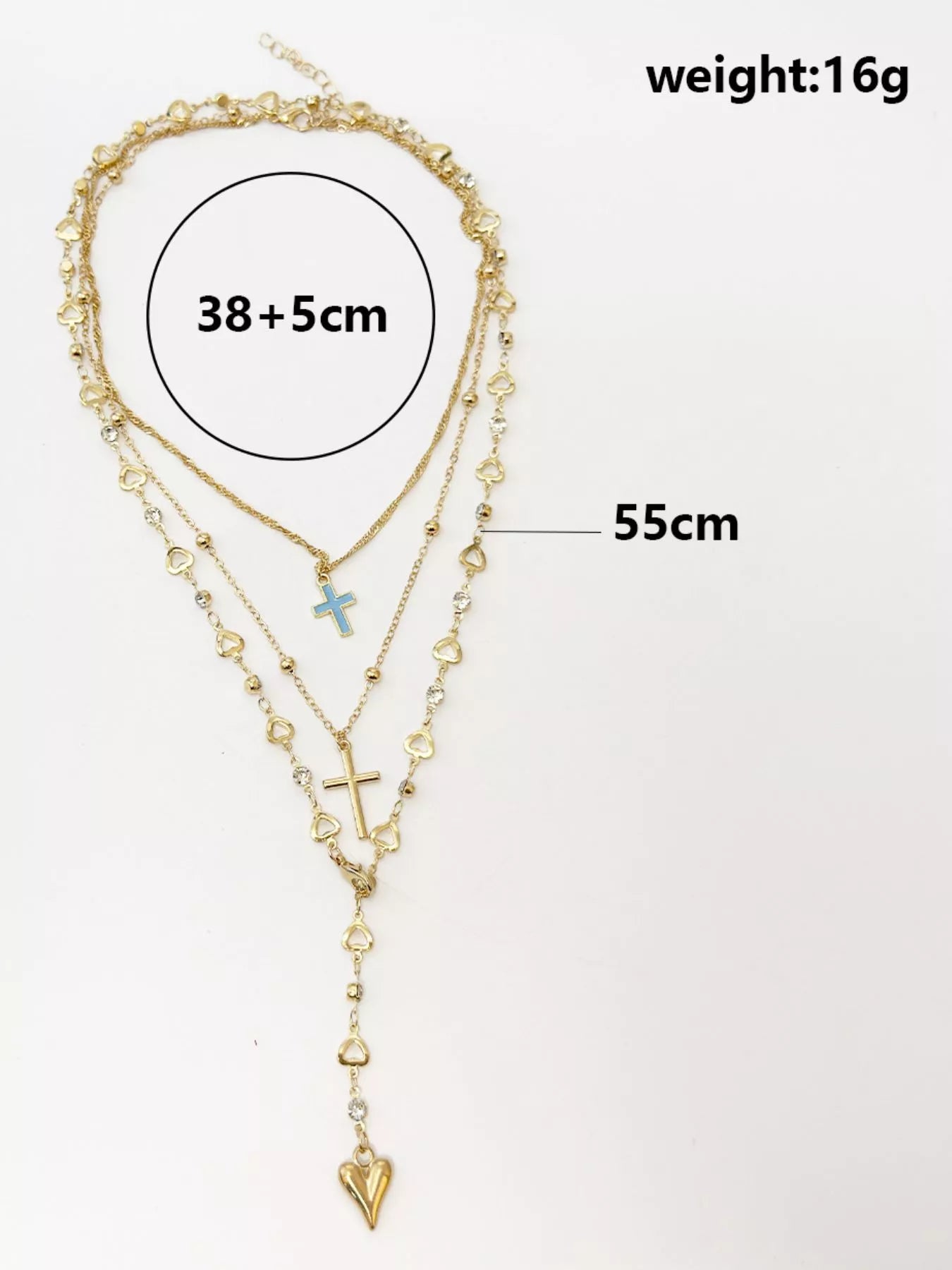 Flat lay of layered gold necklaces with length measurements, blue cross and heart pendant