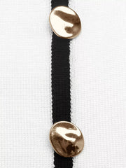 Close up of gold buttons on black placket of white knit top.
