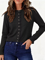 Front view of black ruffle trimmed button down cardigan with ruffled cuffs and dark jeans