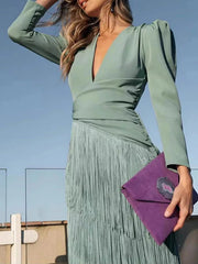 Close front view of a gum leaf green fringed maxi dress with puff sleeves and a purple clutch