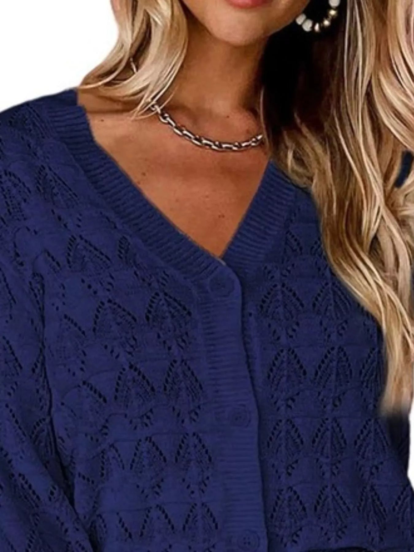 Close view of navy openwork knit cardigan showing V neckline and button front.