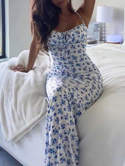 Model seated on bed indoors wearing blue floral print bodycon maxi dress with front tie detail