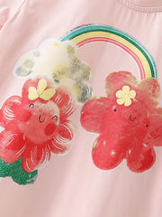 Close-up of smiling red cartoon flowers and rainbow print on blush pink children's tee