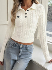 White cable knit long sleeve sweater with polo collar, leaning by a window indoors
