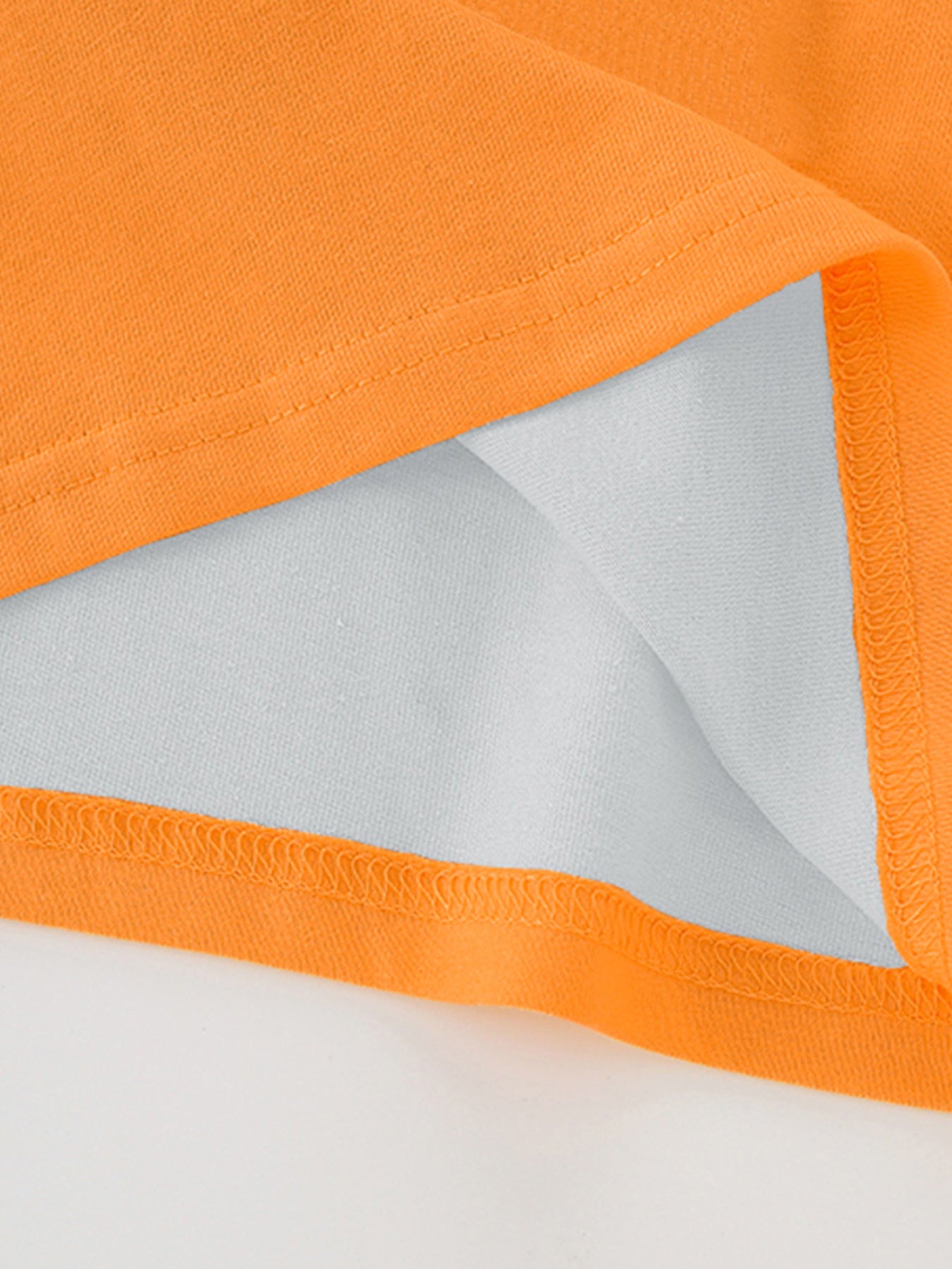 Close-up of the hem stitching and inner fabric on an orange children's excavator graphic T-shirt