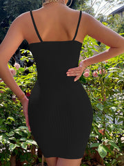 Black ribbed knit tie front mini dress shown from the back in a garden