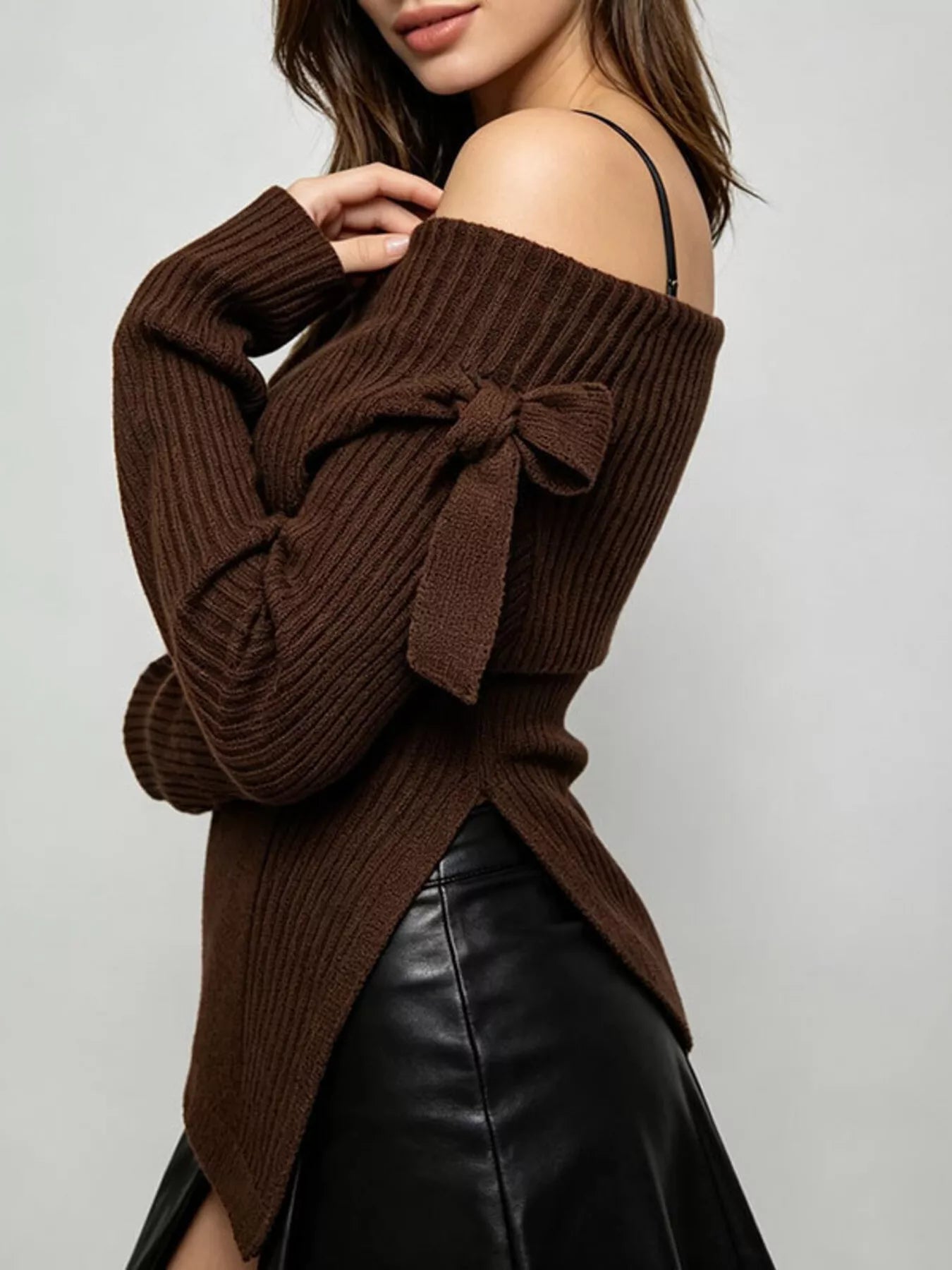 Side view of brown off shoulder ribbed knit top showing bow tie and asymmetric hem