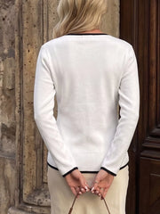 Back view of white long sleeve knit top with black trim at neckline and cuffs.