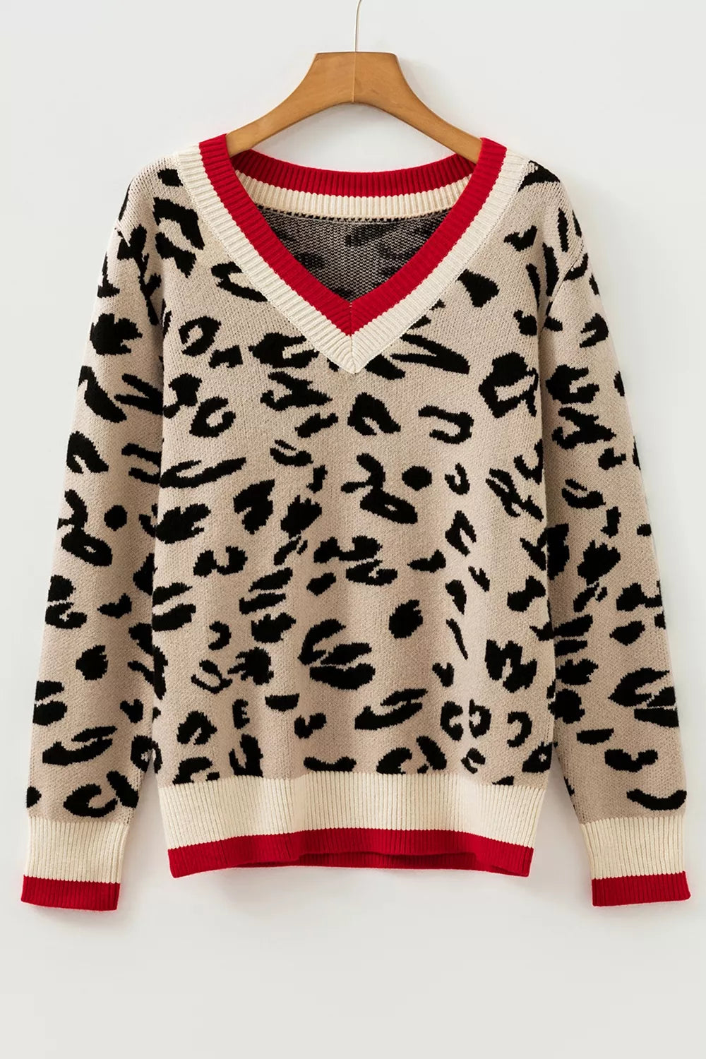 Beige leopard print knit sweater with red and cream V neck trim hanging on a hanger.