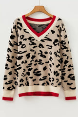Beige leopard print knit sweater with red and cream V neck trim hanging on a hanger.
