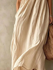 Lower view of a beige one shoulder maxi dress showing the flowing skirt and hem