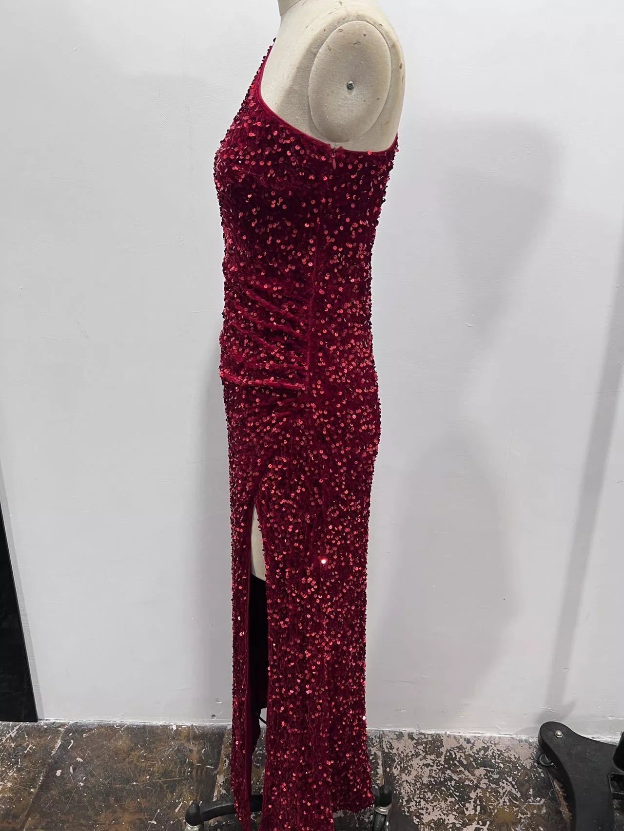 Burgundy sequin one shoulder evening dress shown in a side view on a dress form