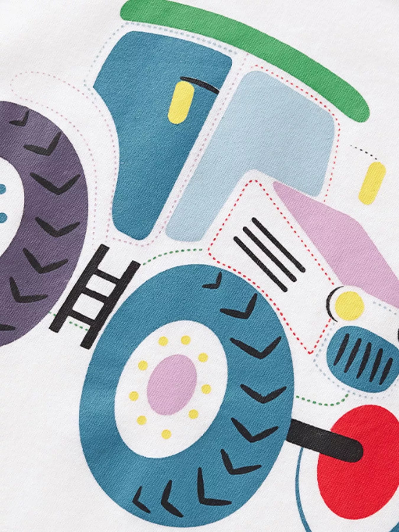 Close up of the cartoon tractor cab and large patterned wheels on the white T-shirt