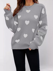 Front view of a gray dropped shoulder sweater with white hearts, one arm raised.
