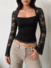 Black square-neck top with sheer floral lace long sleeves and lace-trimmed hem, styled with beige pants